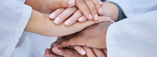 Healthcare team stacking hands in unity and collaboration.&nbsp;