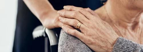Elder care and reassurance shown by a caregiver&rsquo;s hand on the shoulder.&nbsp;