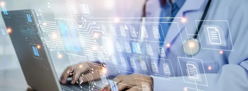 Clinician working on a laptop with an AI-driven document and data interface overlay.&nbsp;