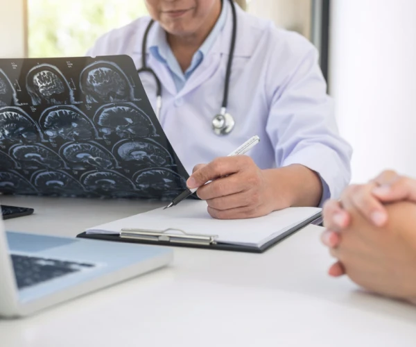 Doctor reviewing brain MRI scans and taking notes during patient consultation.&nbsp;