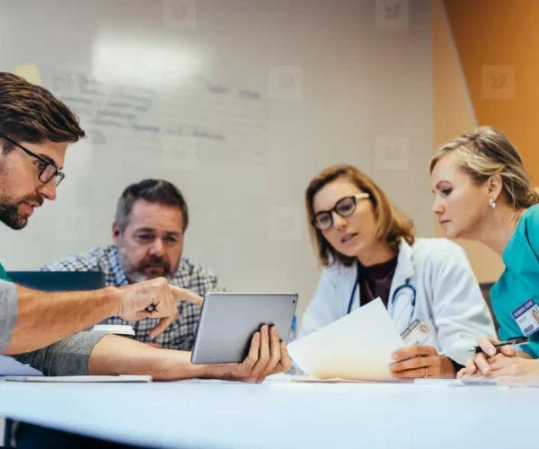 Multidisciplinary hospital team reviewing imaging workflow on a tablet during PACS procurement.&nbsp;
