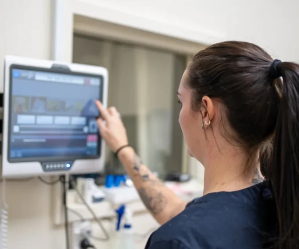 Healthcare professional accessing or updating patient data on a digital touchscreen system in a clinical environment.&nbsp;