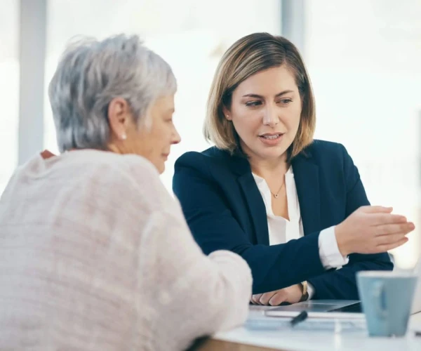 Professional consultation between an advisor and an older woman, reviewing information on a laptop.&nbsp;