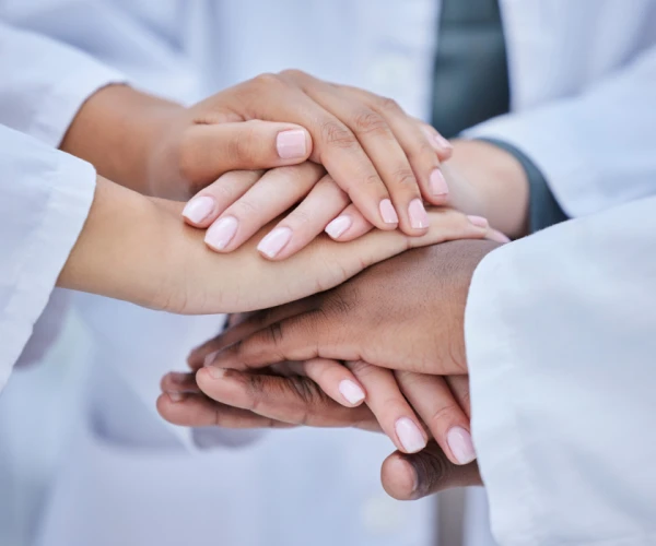 Healthcare team stacking hands in unity and collaboration.&nbsp;