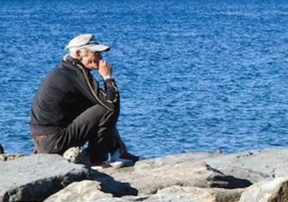 Old man sitting on the breakwater - acciaroli.info