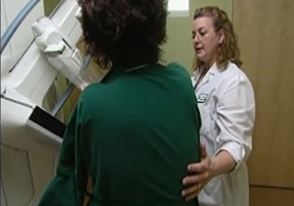 Woman with radiologic technologist during screening mammography exam.