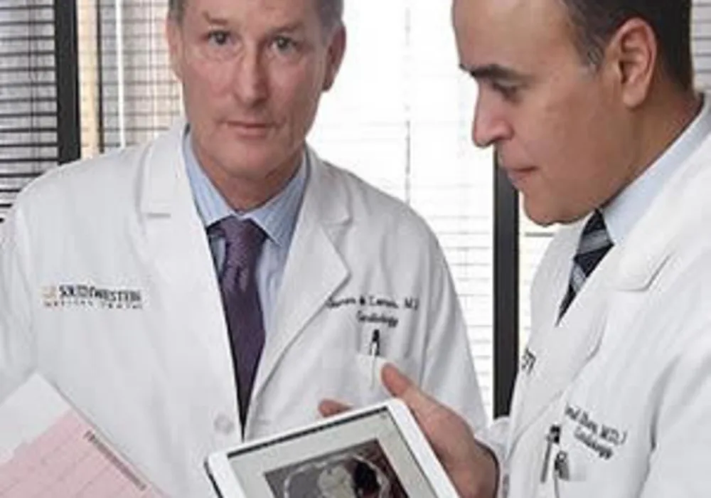 Cardiologists Dr. James de Lemos (left) and Dr. Amit Khera (right) review a printout from an EKG and a calcium scan, two of five tests they demonstrated could improve risk assessment for heart disease.