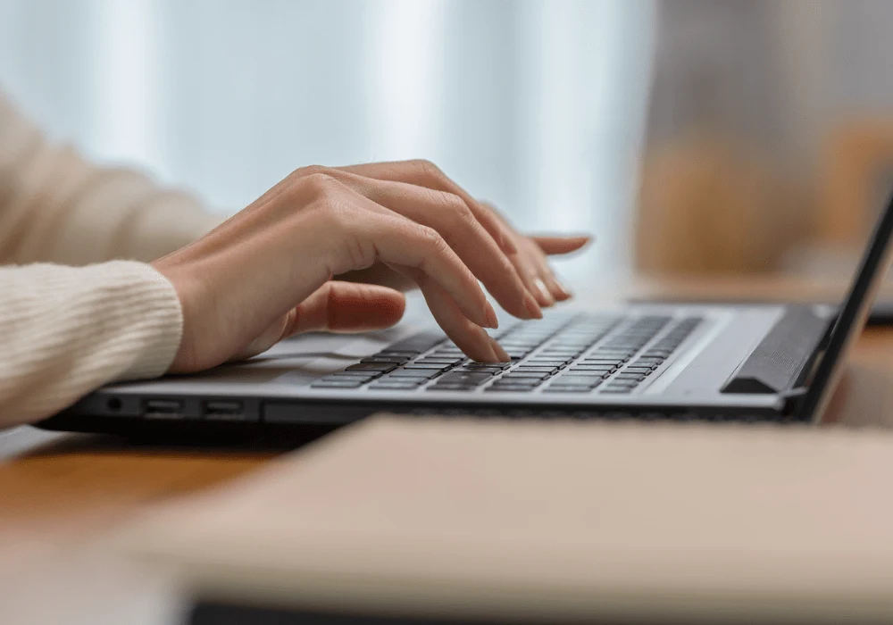 Close-up of hands typing on laptop &ndash; digital communication, remote work and online data entry.&nbsp;
