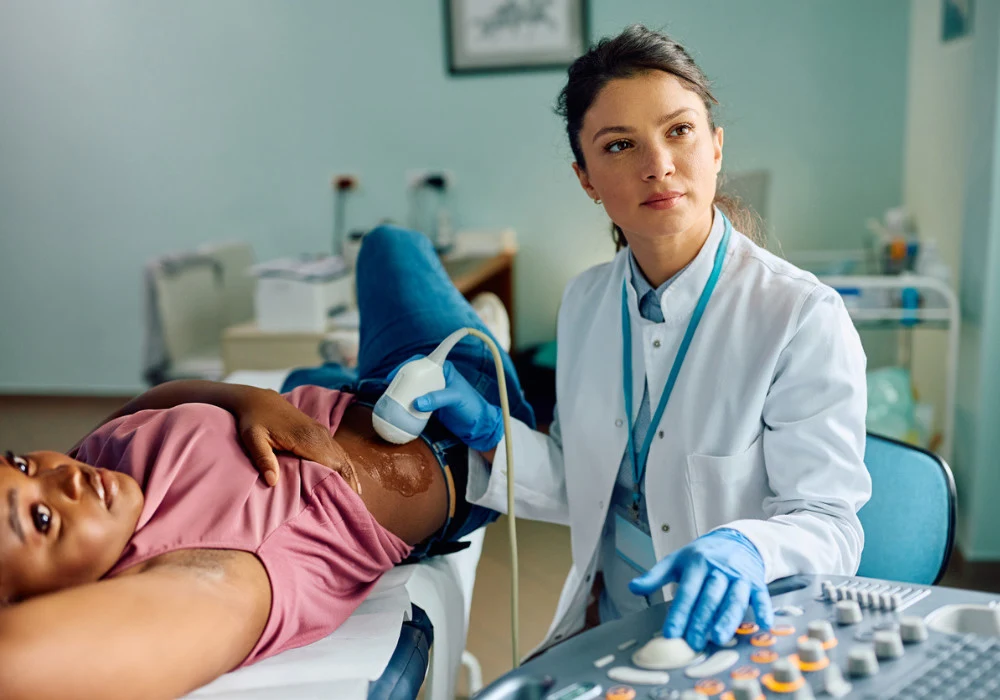 Female doctor performing abdominal ultrasound scan on pregnant woman in medical clinic