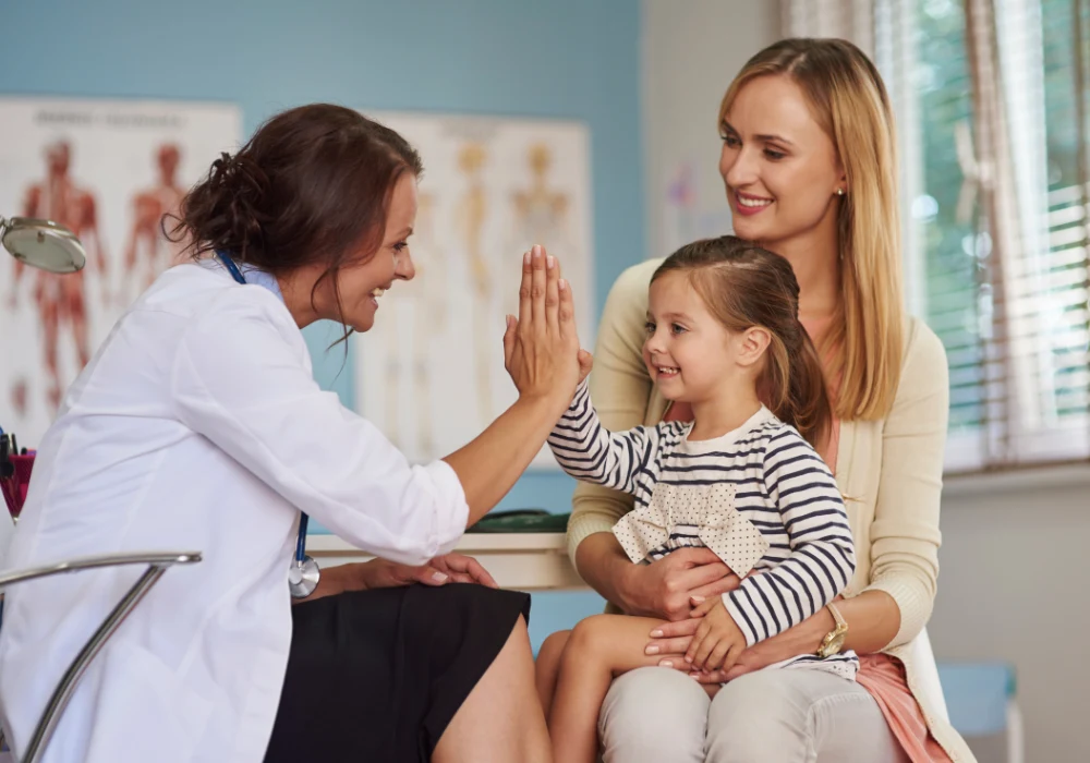 Female doctor consulting mother and child in community clinic setting for paediatric care or vaccination&nbsp;