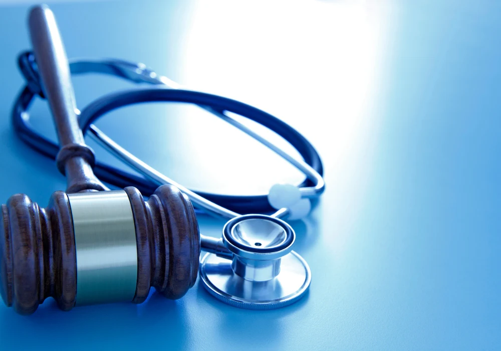 Gavel and stethoscope on blue background symbolising medical law, healthcare regulation and malpractice.&nbsp;