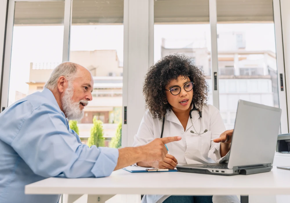 Doctor explaining test results to senior male patient using laptop during medical consultation&nbsp;