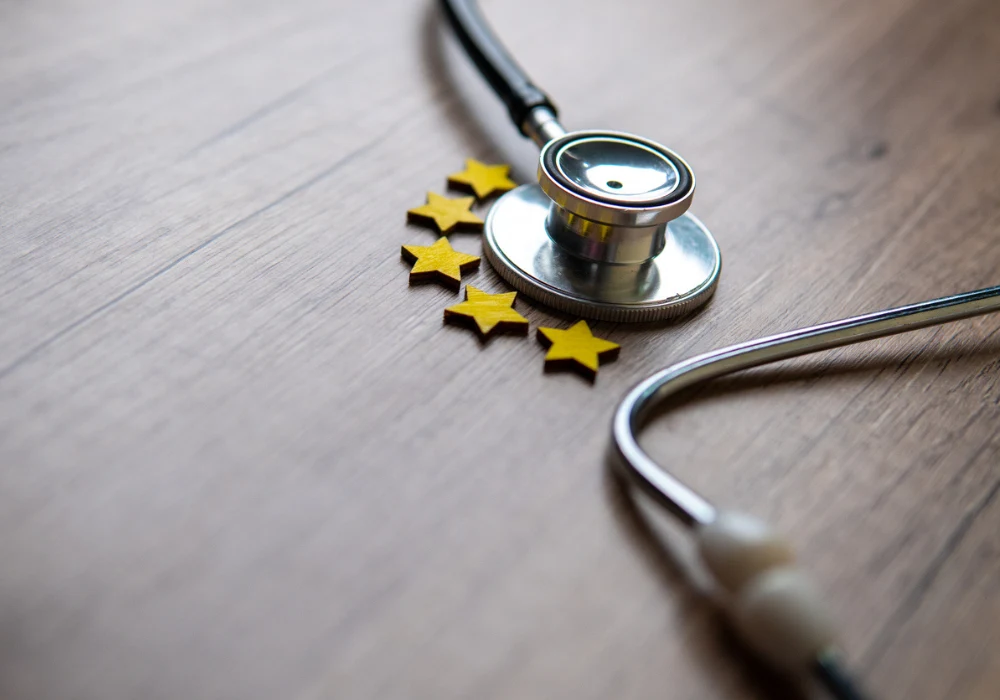 Healthcare quality concept with stethoscope and five-star rating symbol on wooden background.&nbsp;