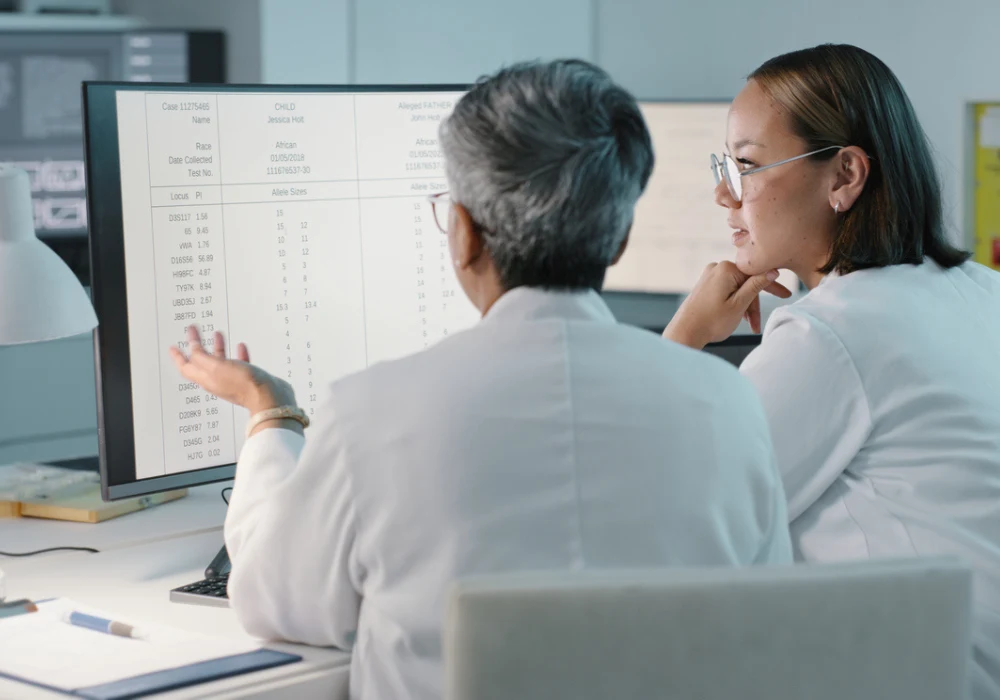 Medical researchers analysing clinical trial data on computer monitors in laboratory setting&nbsp;