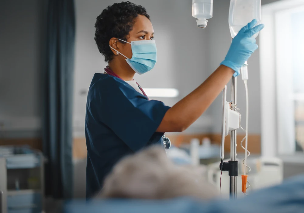Nurse adjusting IV drip for patient in hospital ward&nbsp;