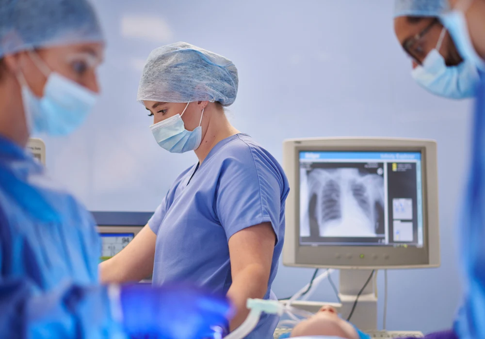 A surgical team in the operating room with an X-ray monitor in the background.&nbsp;