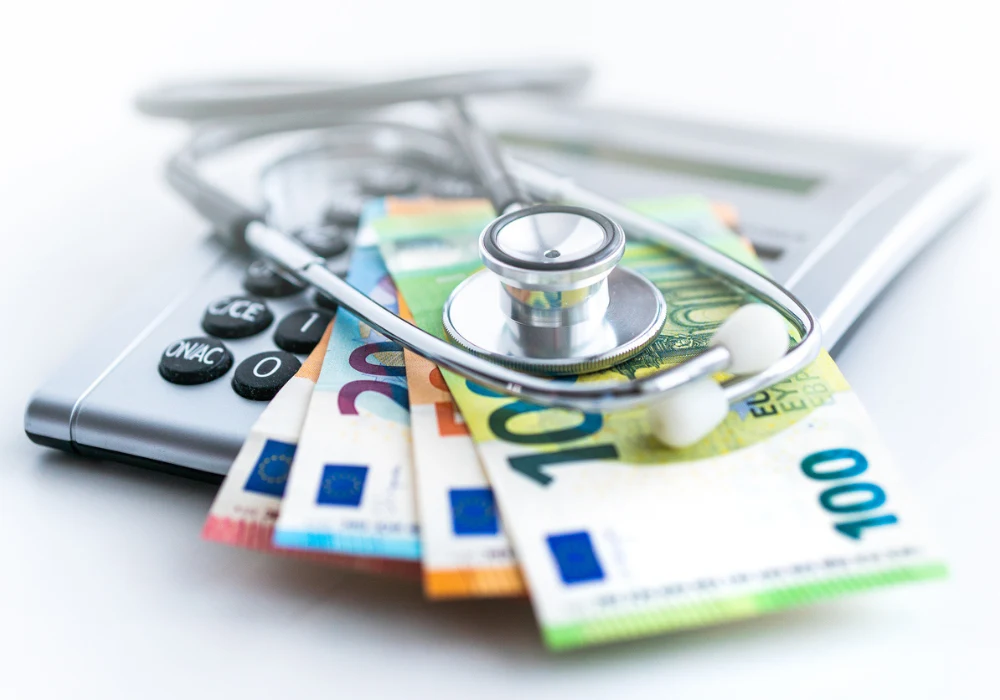Stethoscope placed on euro banknotes and a calculator, symbolising healthcare costs and medical finance.&nbsp;