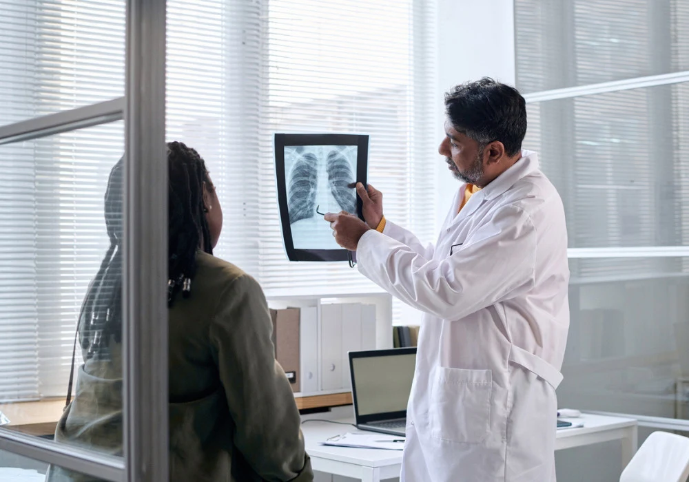 Doctor discusses chest X-ray with a woman in clinic, illustrating lung screening.