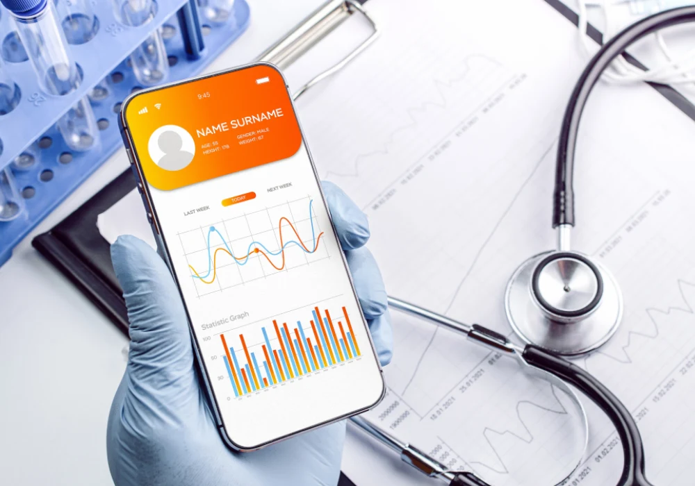 Clinician reviews a smartphone health app with patient analytics, illustrating AI-enabled remote monitoring and point-of-care diagnostics.&nbsp;
