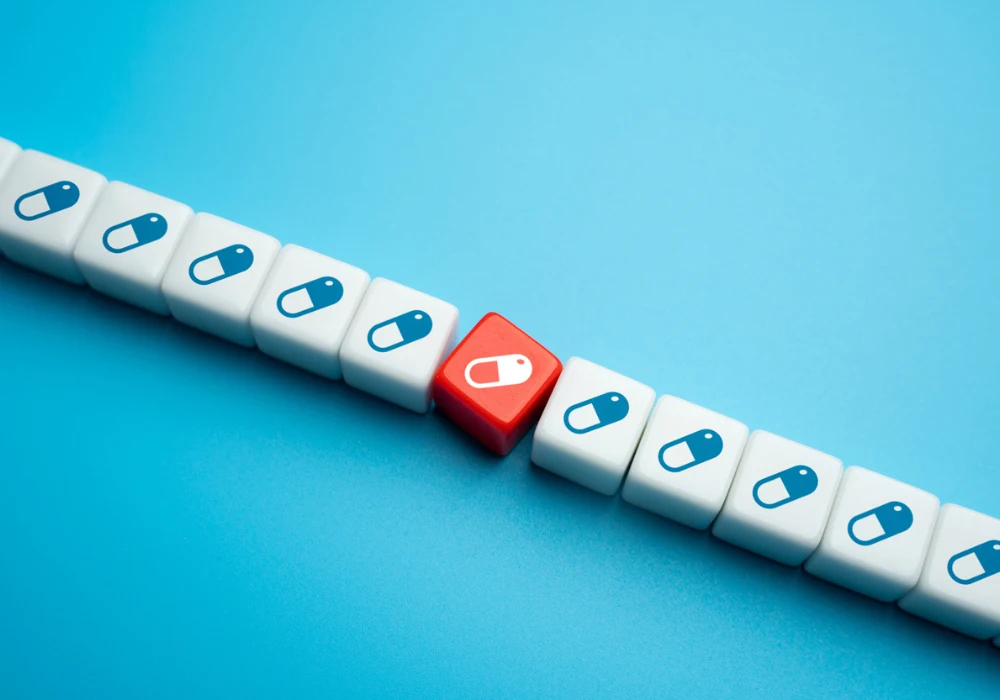 Concept of pharmaceuticals and medical innovation with unique red pill symbol among white cubes, representing drug development and personalised medicine.&nbsp;