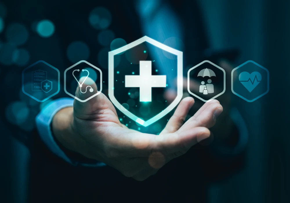 Healthcare cybersecurity shield with medical icons above a clinician&rsquo;s hand, symbolising secure digital transformation. 