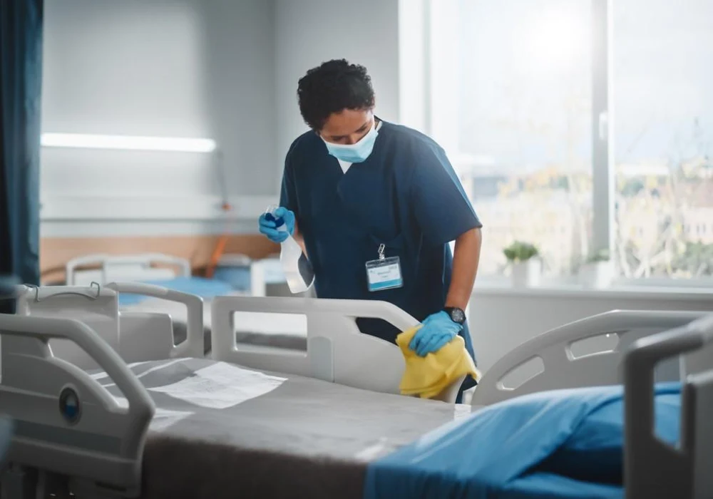 Hospital worker disinfecting a patient bed to ensure hygiene and infection control.&nbsp;