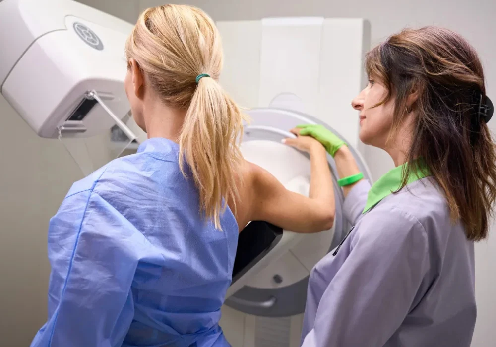 Radiographer positioning a patient for mammography breast imaging in a hospital radiology room.&nbsp;