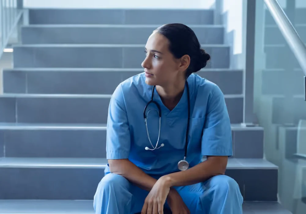 Tired healthcare worker sitting on hospital stairs after a long shift.&nbsp;