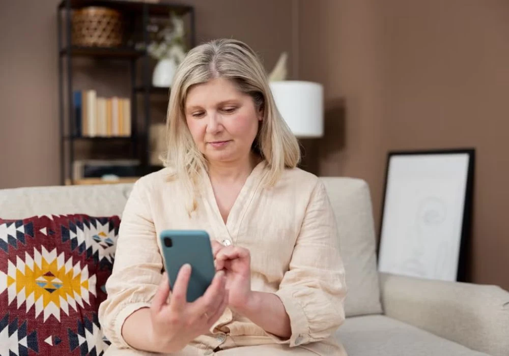 Middle-aged woman using smartphone for telehealth consultation at home.&nbsp;