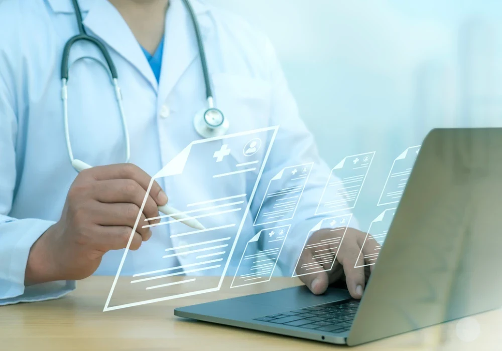 Healthcare professional using a laptop with digital medical icons, symbolising electronic health records, data management and digital transformation in healthcare.&nbsp;
