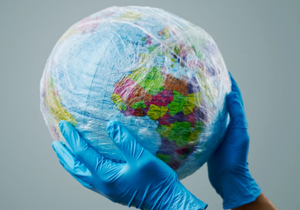 Global health protection concept with gloved hands holding a plastic-wrapped Earth.