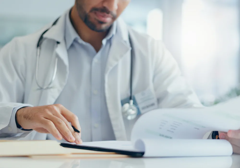 Physician filling out paperwork &ndash; accurate recordkeeping in modern medical practice&nbsp;&nbsp;