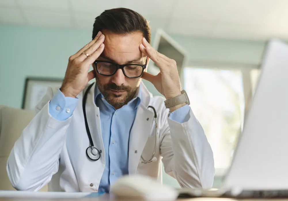 Stressed doctor in a clinical setting, symbolising physician burnout and mental health challenges in healthcare.&nbsp;