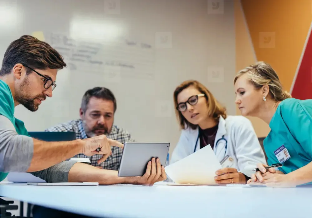 Multidisciplinary hospital team reviewing imaging workflow on a tablet during PACS procurement.&nbsp;