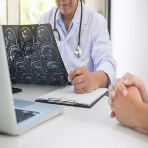Doctor reviewing brain MRI scans and taking notes during patient consultation.&nbsp;