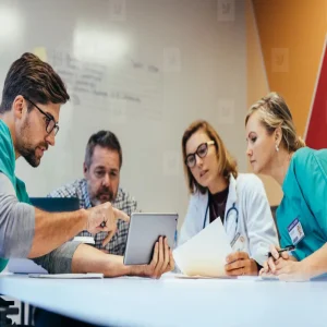 Multidisciplinary hospital team reviewing imaging workflow on a tablet during PACS procurement.&nbsp;