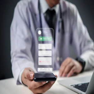 Doctor holding a smartphone displaying a futuristic telemedicine interface with options for video calls, prescriptions, and patient data management.&nbsp;