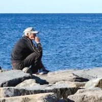 Old man sitting on the breakwater - acciaroli.info