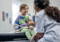 Paediatric check-up &ndash; smiling child with doctor using stethoscope during routine health exam&nbsp;