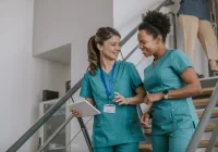 Smiling healthcare workers walking in hospital corridor with tablet for patient care coordination&nbsp;