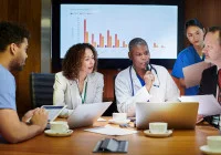 Diverse group of healthcare professionals in a strategy meeting, analysing performance data to improve clinical outcomes, hospital management and patient care quality.&nbsp;