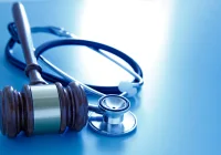 Gavel and stethoscope on blue background symbolising medical law, healthcare regulation and malpractice.&nbsp;