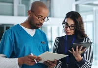 Healthcare team in discussion: administrator reviews digital records with clinical staff.&nbsp;