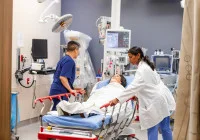 Emergency care team moving patient on stretcher in a high-tech hospital room.&nbsp;