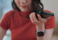Woman using voice assistant on smartphone at home, close-up interaction.&nbsp;