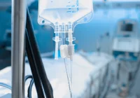 Close-up of IV drip in hospital intensive care unit with blurred patient bed in background&nbsp;