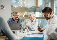 Smiling medical receptionist in scrubs speaking on phone at hospital front desk&nbsp;
