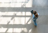 Overhead view of female healthcare worker walking in hospital corridor with digital tablet&nbsp;