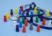Stethoscope surrounded by multicoloured figurines symbolising public health and community care&nbsp;