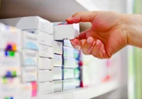 Pharmacist selecting medicine box from shelf in a modern pharmacy&nbsp;